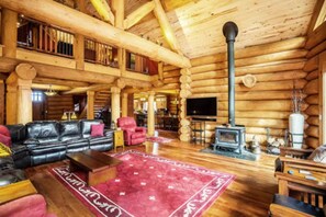 Ein rustikales Blockhaus-Interieur mit Kamin, Ledersofa und Fernseher.