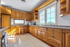 A kitchen with wooden cabinets, a granite countertop, and a window with a view.
