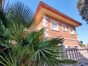 A brick building with a red roof and white window frames.
