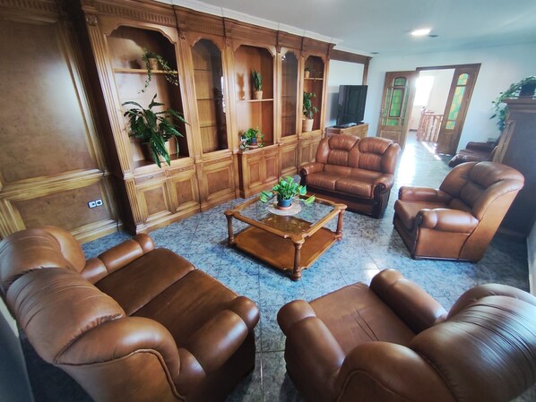 A living room with leather sofas, a coffee table, and wooden shelving with plants.