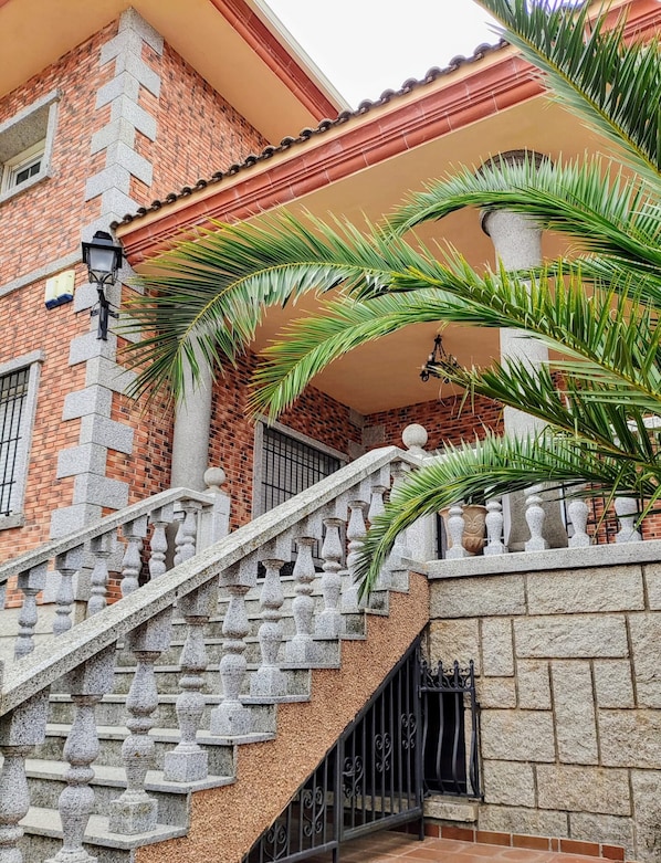 A staircase with stone balustrades leading to a brick building with a tiled roof.