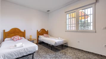 Una habitación de hotel con dos camas individuales, ventana con vistas y suelo de baldosas.