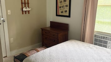 Une chambre à coucher comprenant un lit, une commode, une étagère fixée au mur et une affiche encadrée.