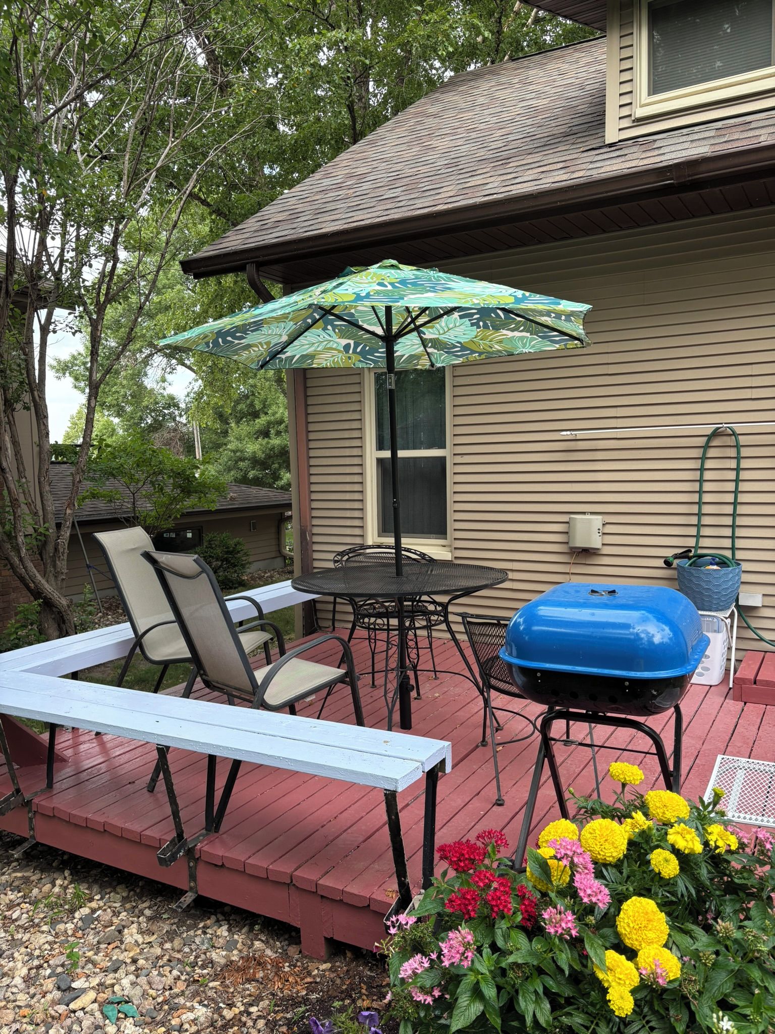 Une terrasse dotée de mobilier d’extérieur, d’un barbecue et d’un parterre de fleurs.