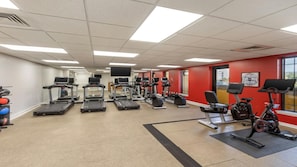 Une salle de sport équipée de tapis de course, d’appareils elliptiques et de vélos d’appartement.