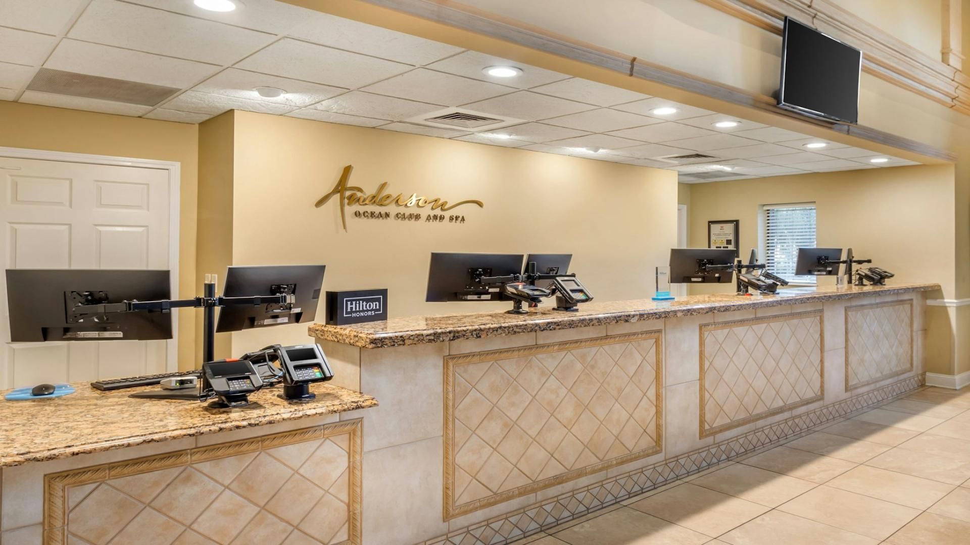 A hotel reception area with a counter, reception desk, and a wall sign.