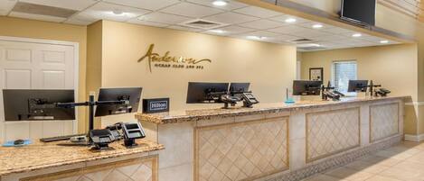 A hotel reception area with a counter, reception desk, and a wall sign.