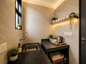 A modern bathroom with a sink, faucet, and a shelf with plants and a kettle. - TerraTrek Ayodhya Greens (Faizabad)