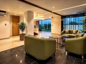 Un vestíbulo moderno con asientos de cuero, una mesa de recepción y un amplio ventanal con vistas al exterior.