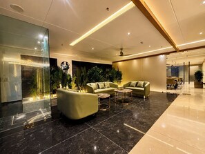 Un lobby moderno con zona de estar, mostrador de recepción y pared de vidrio.