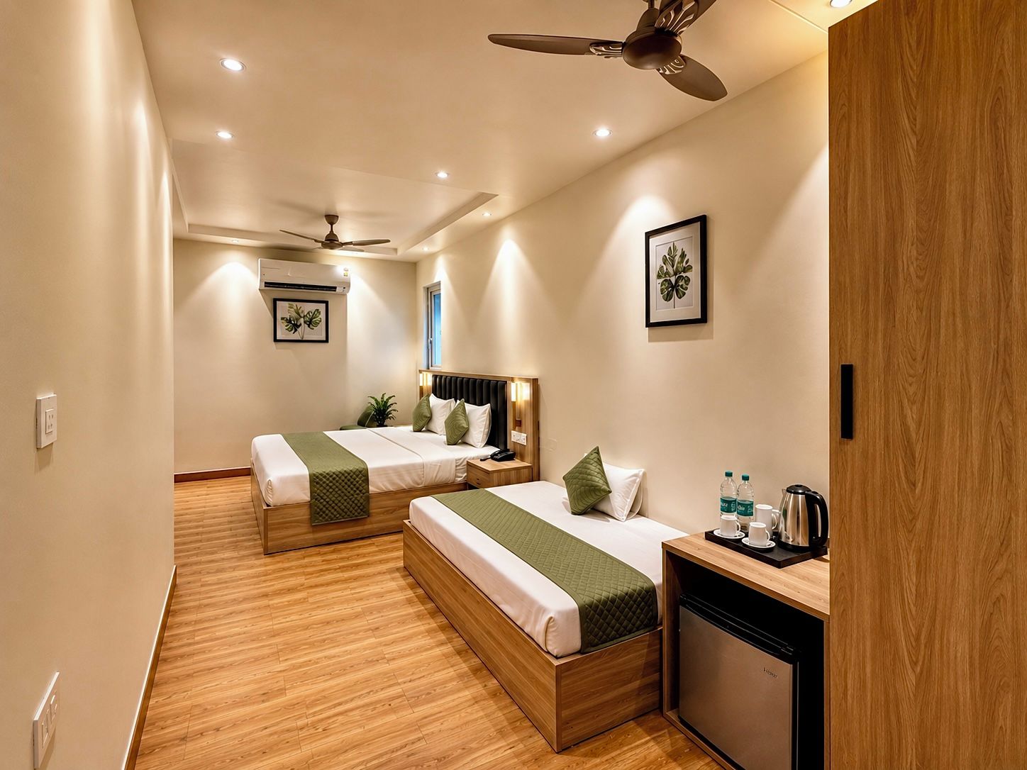 A hotel room with two beds, a desk, a coffee maker, and a ceiling fan.