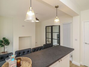 A modern kitchen with a dark countertop, two pendant lights, a built-in oven, and a window with blinds. - No.40 Rufford Road (Nottingham)