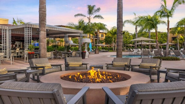 An outdoor seating area with lounge chairs and a central fire feature.