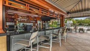Un espace bar avec un comptoir, des sièges et une vue sur la terrasse extérieure.