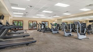 Une salle de sport équipée de tapis de course, de vélos elliptiques et d'appareils de musculation.