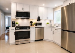 A modern kitchen with white cabinets, stainless steel appliances, and a dishwasher. - Spacious 5BR, Near NYC, Reserved Parking & Yard (Jersey City)