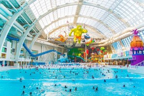 Ein großes Hallenbad mit mehreren Bahnen, hoher Decke und verschiedenen Wasserrutschen.