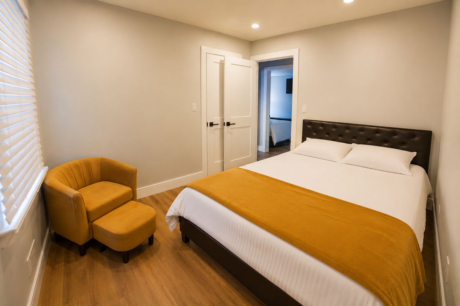 A bedroom with a bed, a chair, and a door leading to a bathroom.