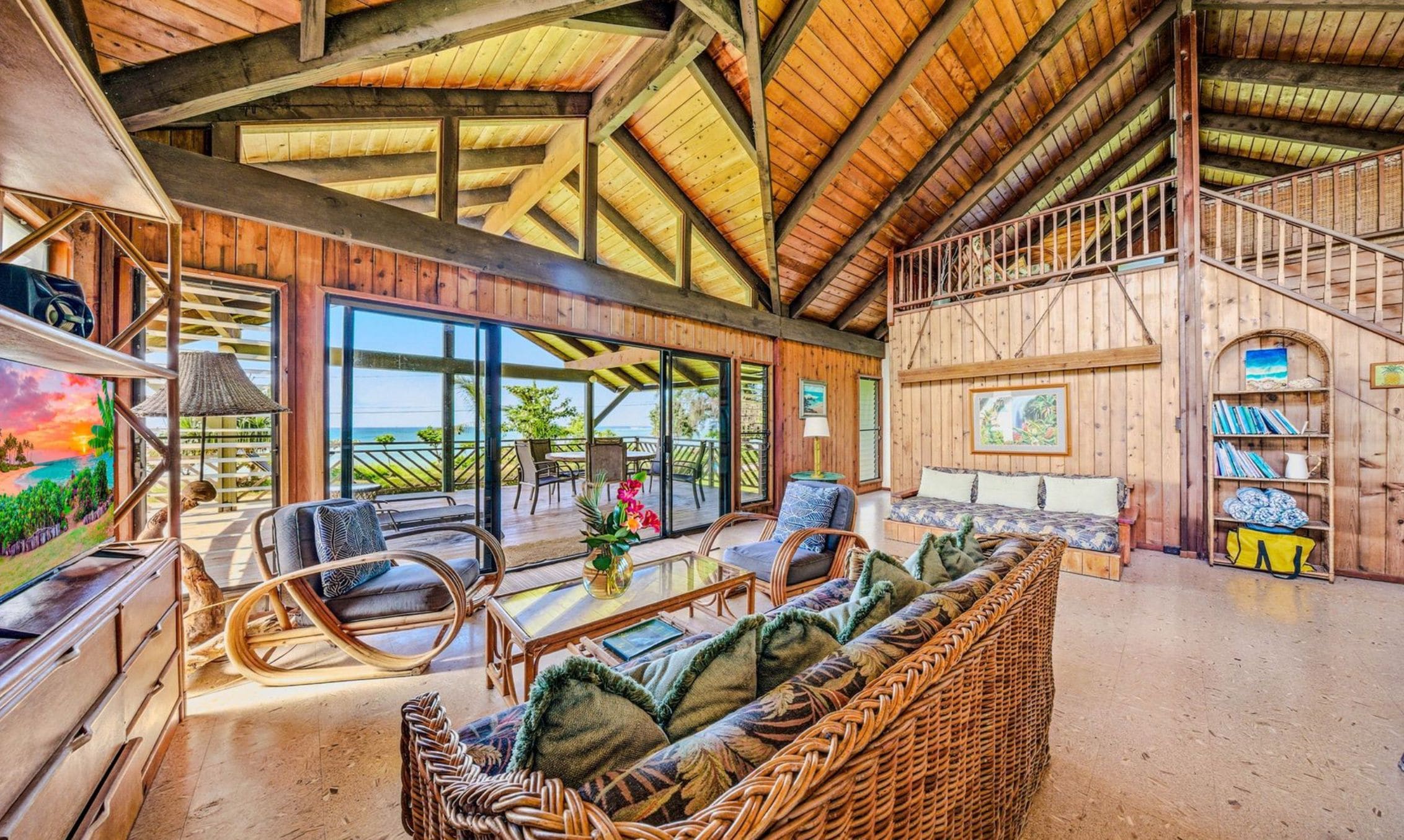 A spacious living area with a high ceiling, large windows, and a view of the outdoors.