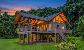 A two-story wooden cabin with a balcony and a covered patio area.