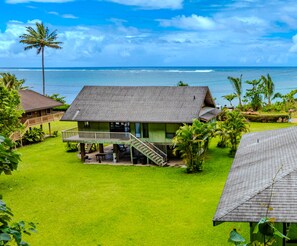 A beachfront property with a two-story house, a covered patio, and a view of the ocean.