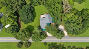 An aerial view of a residential property with a house, a driveway, and surrounding greenery.