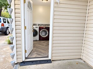 A laundry room with two washing machines, a door, and a vehicle parked outside.