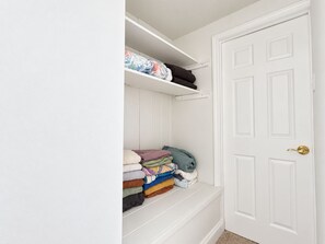 A white closet with shelves and a door.