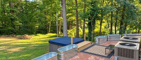 An outdoor patio with a hot tub, seating area, and outdoor air conditioning units.