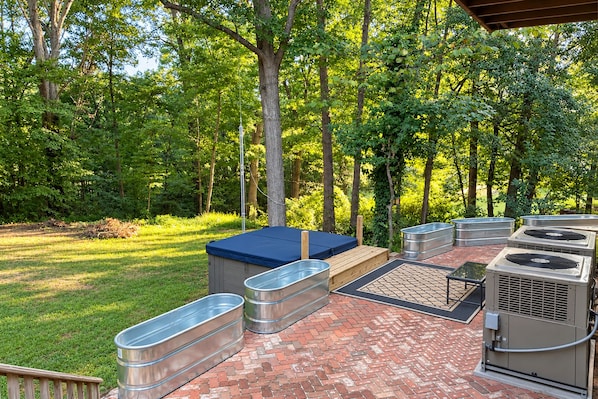 An outdoor patio with a hot tub, seating area, and outdoor air conditioning units.