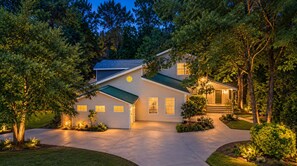A two-story house with a covered garage, surrounded by trees and a well-maintained lawn.