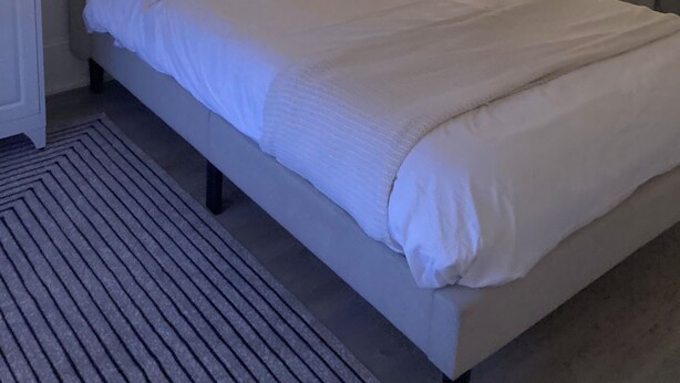 Un lit avec une tête de lit, une table de chevet et une petite table à poser près du lit.