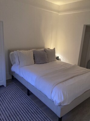 A bed with a headboard, a bedside table, and a nightstand.