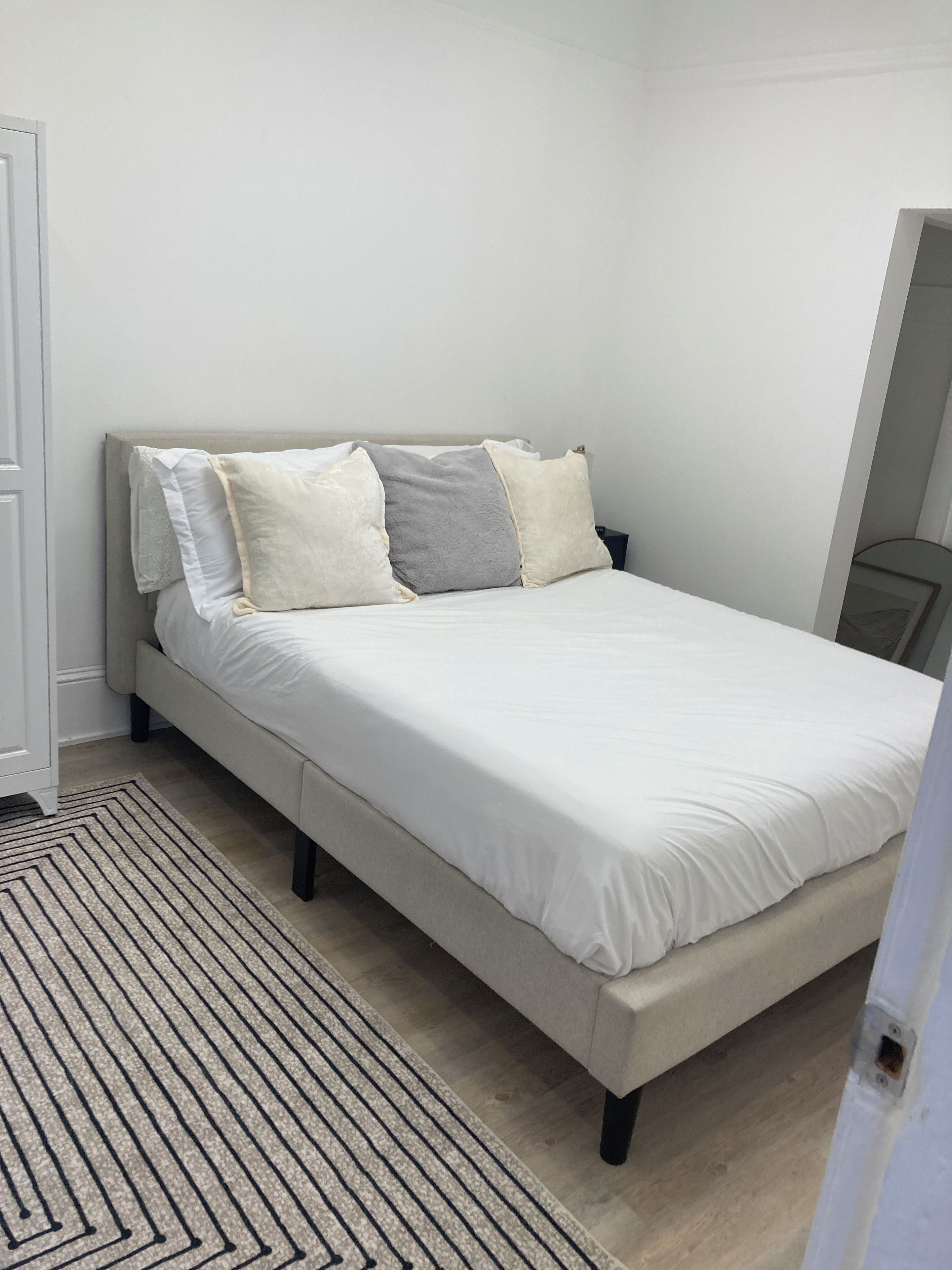 A bedroom with a bed, a headboard, a bedside table, and a floor lamp.