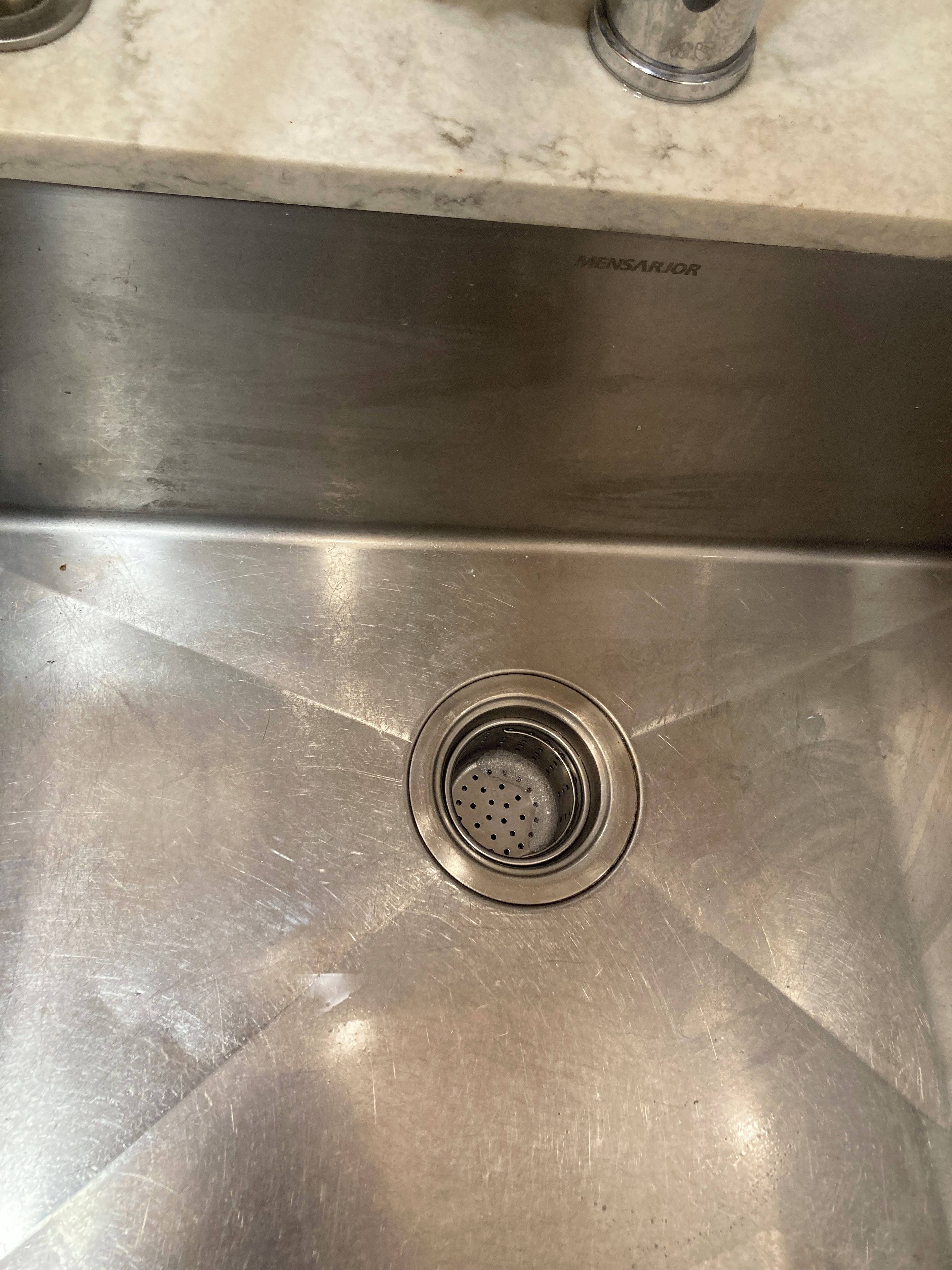 A stainless steel kitchen sink with a built-in strainer.