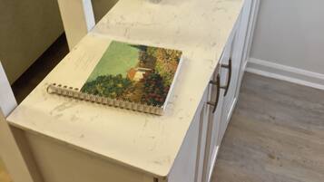 Un cuaderno sobre una encimera de mármol con un espejo encima.