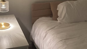 Une chambre à coucher avec un lit, une table de chevet avec une lampe et une étagère fixée au mur.