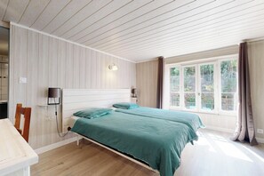 Ein Schlafzimmer mit zwei Betten, einem Schreibtisch, einem Stuhl, einer Lampe und einem Fenster mit Vorhängen.