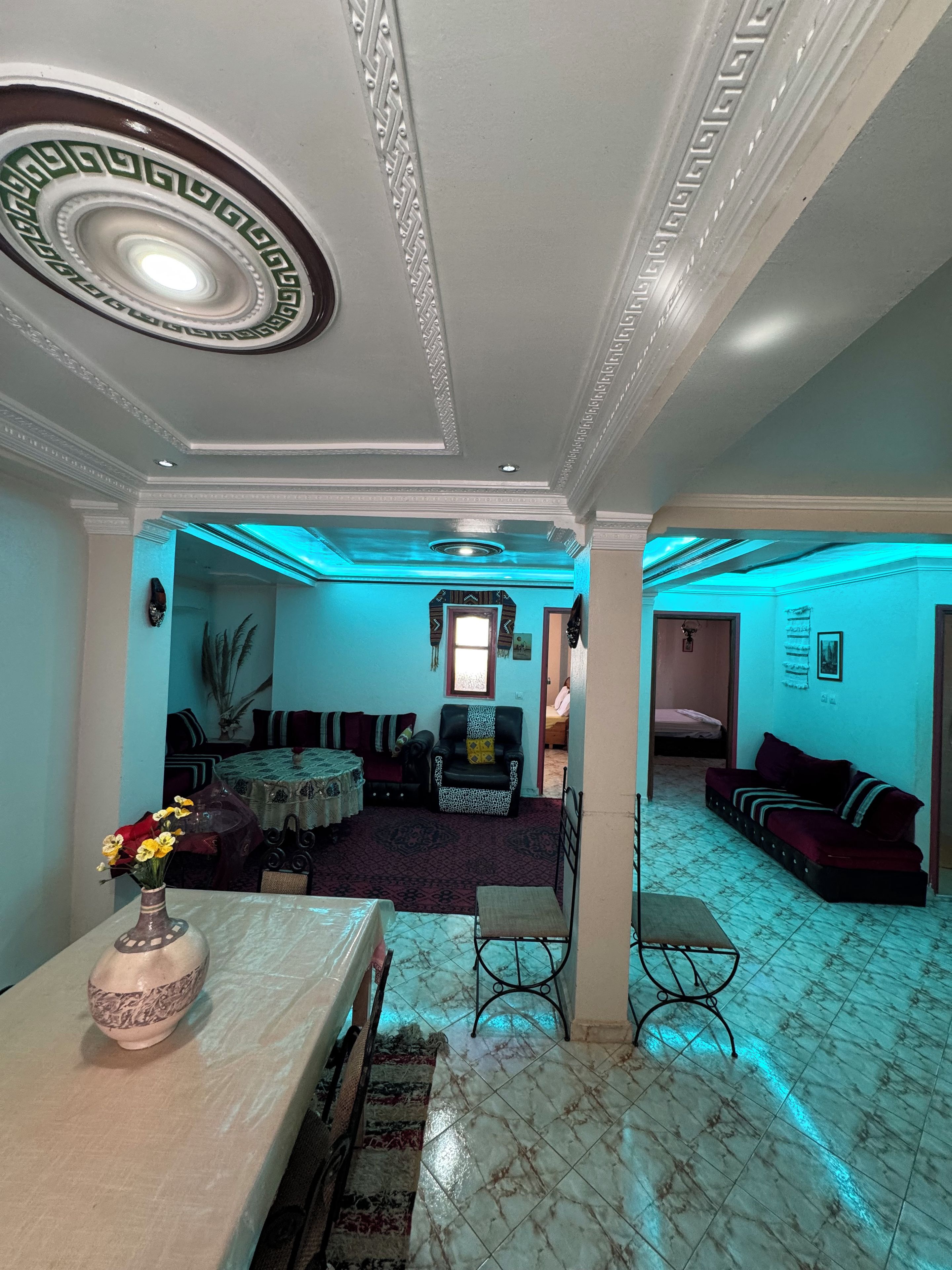 Une pièce comprenant une table à manger, un canapé, un tapis à motifs et un plafond décoratif.
