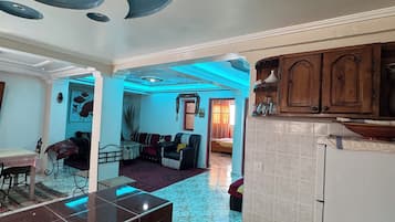 A spacious living area with a kitchen, a dining area, and a visible doorway leading to another room.