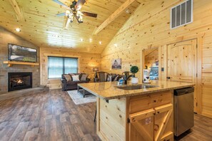 A cozy cabin interior with a fireplace, wooden walls, a dining area, and a kitchen. - Mt views, king bed, hot tub & 2 fireplaces. Minutes to Gatlinburg attractions. (Gatlinburg)