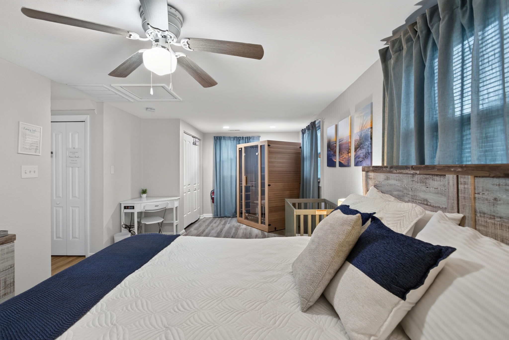 A bedroom with a large bed, a desk, and a wardrobe.