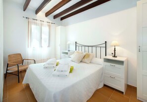 A hotel room with a bed, two bedside tables with lamps, a chair, and a wardrobe. - Spacious Countryside Villa, A/C, Private Pool, Magnificent Views of s'Albufereta & Bay of Pollença! (Alcudia)