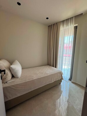 Une chambre à coucher avec un lit, une fenêtre avec des rideaux et une porte.