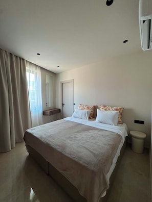 Une chambre à coucher comprenant un lit, une table de chevet, un miroir, une fenêtre avec des rideaux et des toilettes.