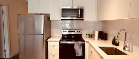 Cocina moderna con electrodomésticos de acero inoxidable, microondas, horno y lavaplatos.