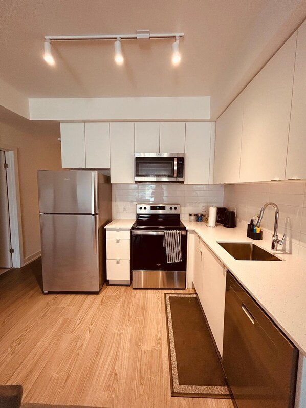 A modern kitchen with stainless steel appliances, a microwave, oven, and a sink.