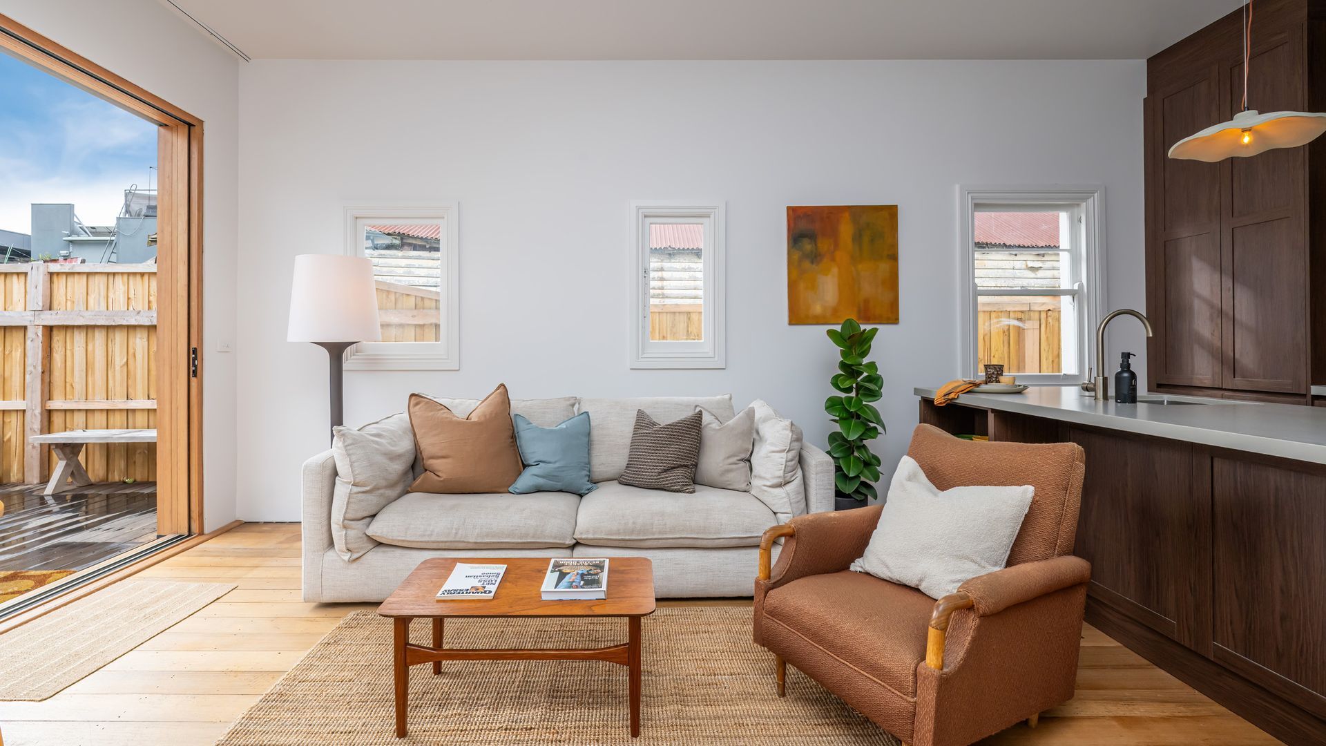 Ein Wohnzimmer mit Sofa, Sessel, Couchtisch und Blick ins Freie.