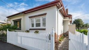A two-story house with a white picket fence, a brick chimney, and a stone pathway leading to the entrance. - Bellamy Richmond by Property Mums (Richmond)