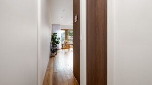 A hallway with wooden flooring leading to a dining area with a table and chairs. - Bellamy Richmond by Property Mums (Richmond)